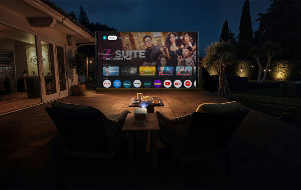 JMGO N1S 4K outdoor projector in backyard displaying Google TV on a large screen