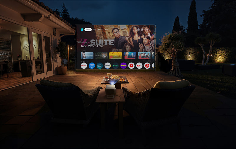 JMGO N1S 4K outdoor projector in backyard displaying Google TV on a large screen